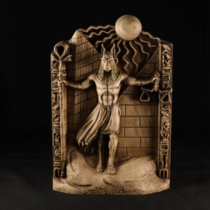 May include: A wooden sculpture of Anubis, the Egyptian god of the dead, holding a staff and scales. The sculpture is carved in a detailed style and features hieroglyphics on the sides.