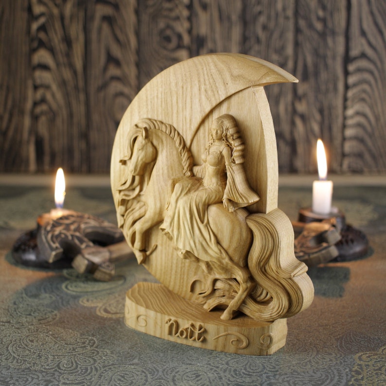 May include: A wooden carving of a woman riding a horse, with the word "Natt" carved below. The carving is on a crescent moon-shaped base.