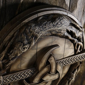May include: A wooden shield with a carved wolf design and a Celtic knot pattern. The shield is brown and has a distressed finish.