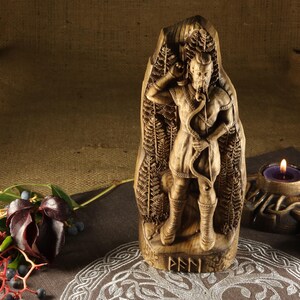 May include: A wooden carving of a Norse god, possibly Odin, with a beard and holding a bow and arrow. The carving is surrounded by a fern pattern and the word "FEN" is inscribed at the bottom.