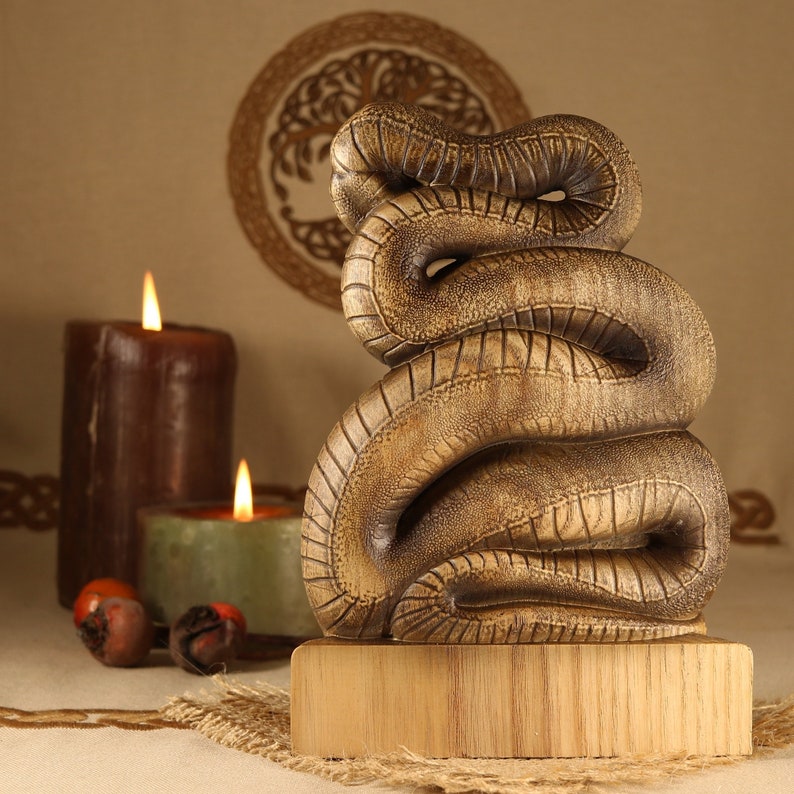 May include: A wooden sculpture of a snake coiled in a spiral shape. The sculpture is brown and has a textured surface. It is sitting on a wooden base.