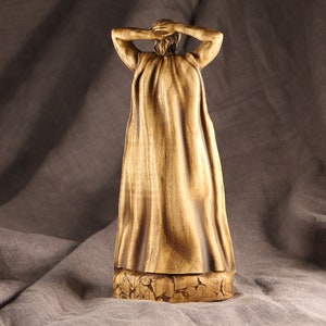 K&ouml;nnte beinhalten: Eine Holzfigur einer Person, die eine lange, flie&szlig;ende Robe tr&auml;gt. Die Figur ist realistisch geschnitzt und hat eine warme, braune Farbe.