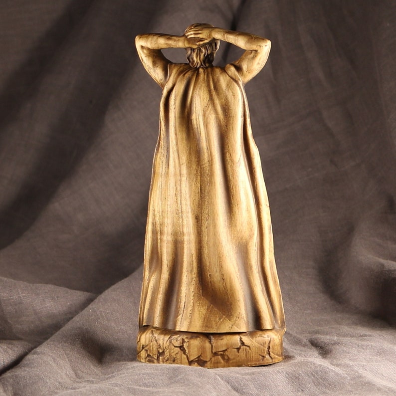 K&ouml;nnte beinhalten: Eine Holzfigur einer Person, die eine lange, flie&szlig;ende Robe tr&auml;gt. Die Figur ist realistisch geschnitzt und hat eine warme, braune Farbe.
