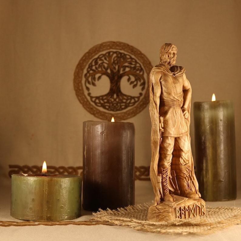 May include: A wooden carving of a Viking warrior standing on a base with the word "BEORNIX" inscribed. The warrior is wearing a cloak and holding a sword. The carving is surrounded by three candles, two brown and one green.