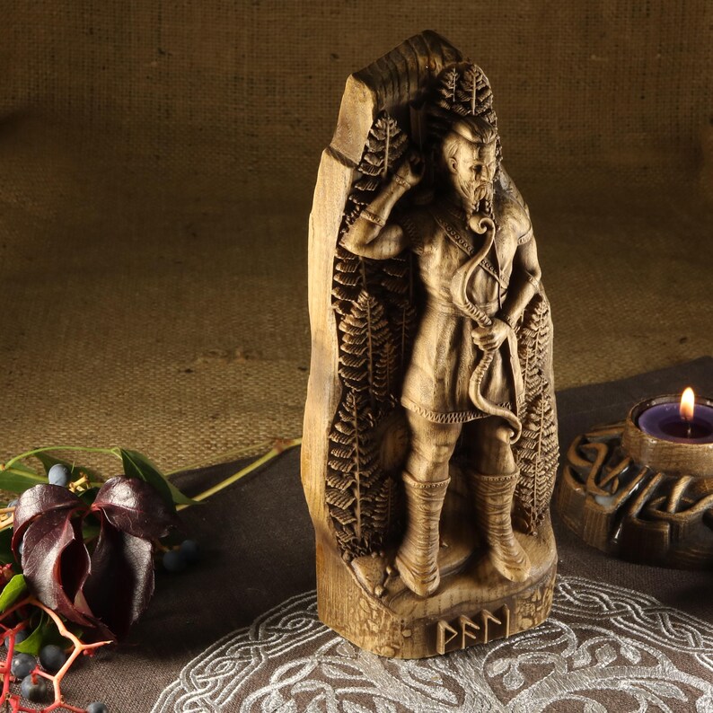 May include: A wooden carving of a Norse god, possibly Odin, holding a bow and arrow. The carving is detailed and features intricate designs. The carving is standing on a wooden base with the word "PFNN" inscribed on it.