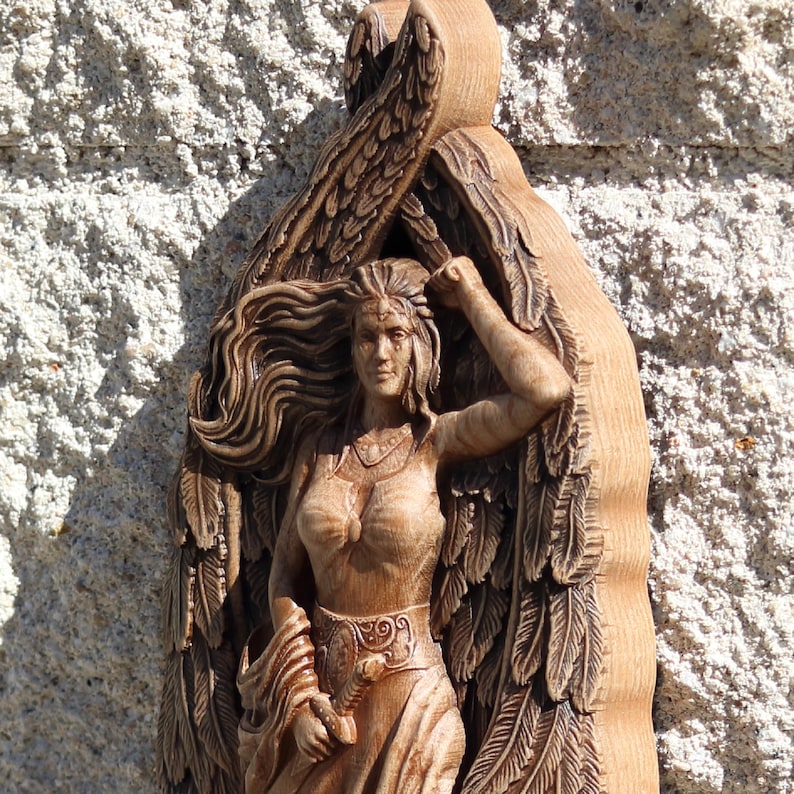 May include: A wooden carving of a woman with wings, her hair flowing behind her. The carving is detailed and intricate, with a focus on the woman's face and flowing hair.
