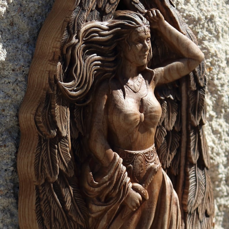 May include: A wooden carving of a woman with flowing hair and wings. The carving is detailed and intricate, with a focus on the woman's face and hair.