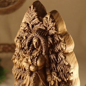 May include: A wooden sculpture of a woman with a crown of leaves, surrounded by carved foliage. The sculpture is detailed and intricate, with a realistic depiction of the woman's face.
