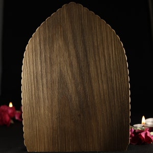 May include: A wooden plaque with a scalloped edge, perfect for displaying a message or artwork. The plaque is a dark brown color and has a natural wood grain.