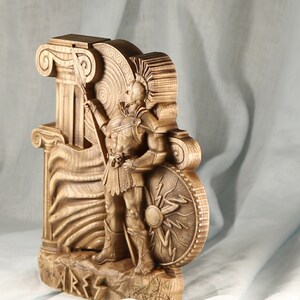 Close-up side view of wooden Ares statue, high-relief wood carving panel of Greek god of war, ancient Greek mythology altar decor, carved Ionic columns, dark stained wood.