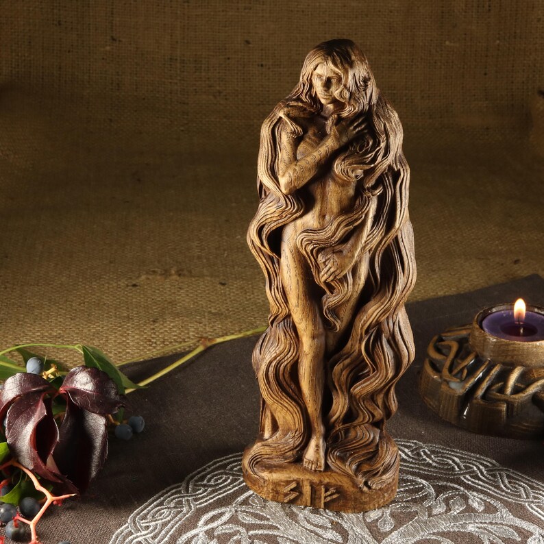 May include: A wooden sculpture of a woman with long flowing hair. The sculpture is carved in a detailed style and has a warm brown color.