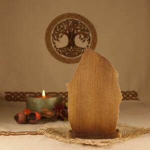May include: A wooden sign with a rustic brown finish, standing on a burlap base. The sign is blank and ready to be personalized. The sign is in front of a background with a Celtic knot design.