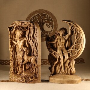 May include: Two wooden carvings, one depicting a figure standing in a forest and the other a figure standing in a crescent moon. Both carvings are detailed and intricate.