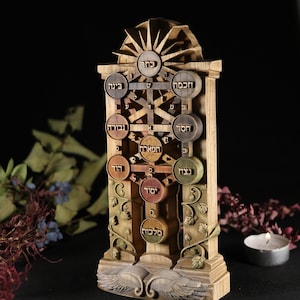 May include: A wooden carving of the Tree of Life, a Kabbalistic symbol, with Hebrew text on each of the ten sefirot. The carving is on a wooden base with wings.