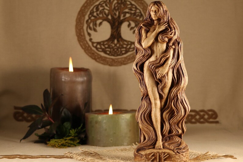 May include: A wooden sculpture of a woman with long flowing hair. The sculpture is carved in a detailed style and is standing on a base with the word "Sig" carved into it. The sculpture is surrounded by candles and a wooden tree of life.