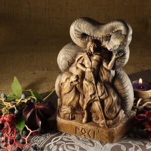 May include: Wooden sculpture of a female figure standing with a snake wrapped around her, a bear at her feet, and the word "RAKI" carved on the base.