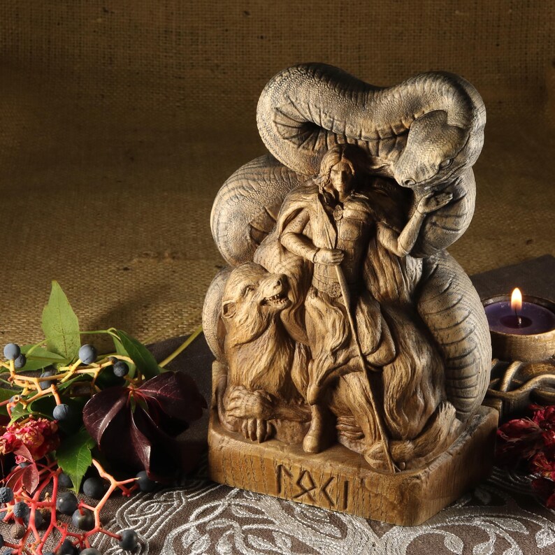 May include: Wooden sculpture of a female figure standing with a snake wrapped around her, a bear at her feet, and the word "RAKI" carved on the base.