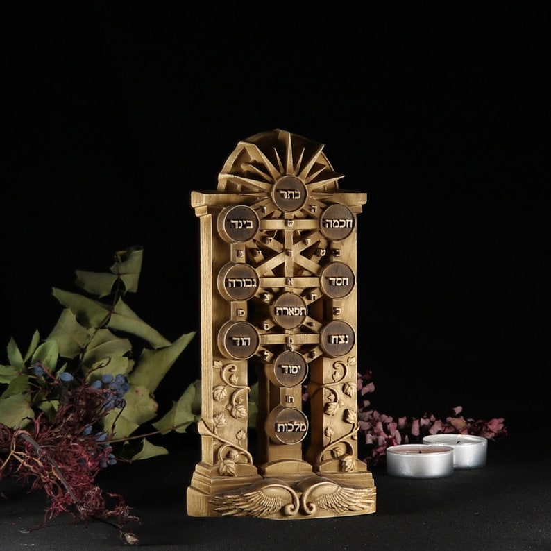May include: A wooden sculpture of the Tree of Life, a Kabbalistic symbol, with Hebrew letters inscribed on each circle. The sculpture is carved with intricate details and features a sunburst design at the top.