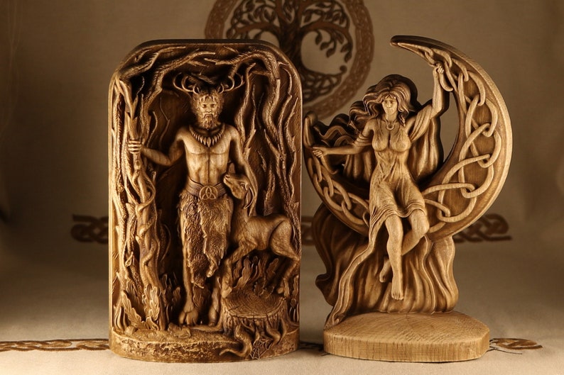 May include: Two wooden carvings depicting a horned god and a goddess. The god is standing in a forest scene, holding a staff and a deer. The goddess is sitting on a crescent moon, with her arms raised.