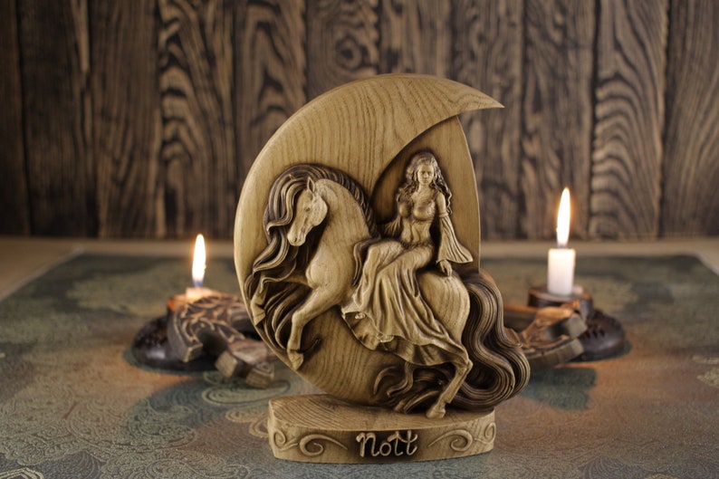 May include: A wooden carving of the Norse goddess Nott riding a horse, with the name "Nott" inscribed on the base. The carving is set against a wooden background with two lit candles.
