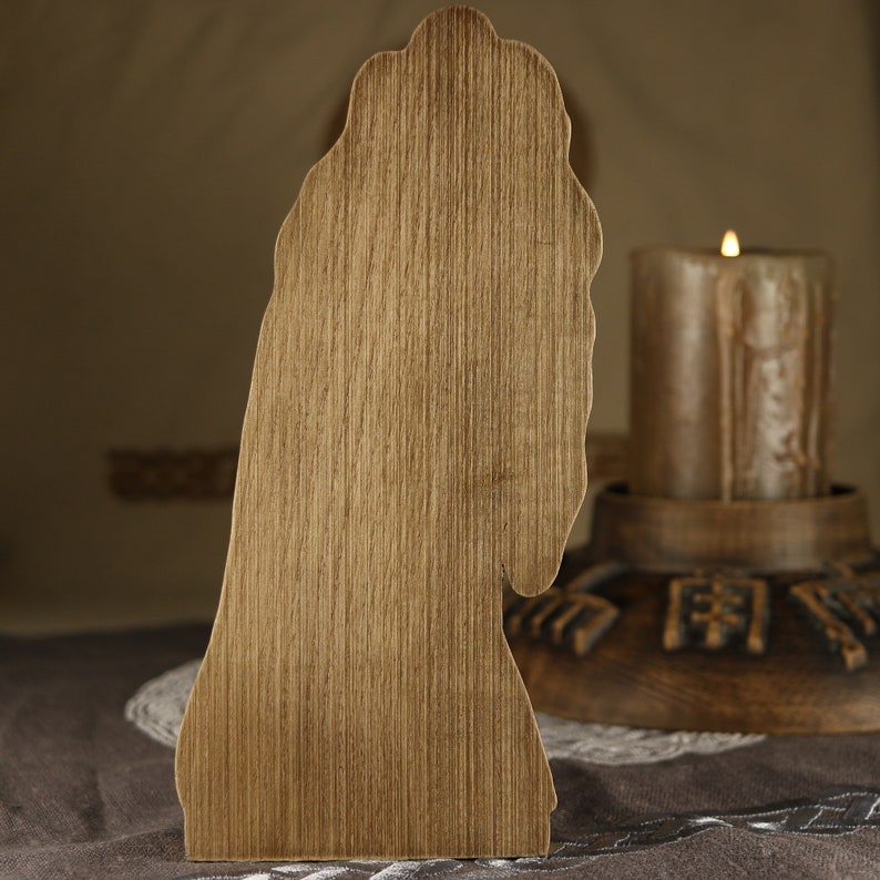 Puede incluir: Corte de madera de una persona con el pelo largo, de pie frente a una vela encendida sobre una base de madera.