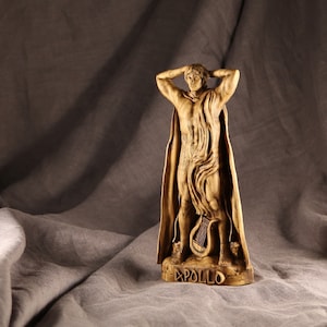 K&ouml;nnte beinhalten: Eine Holzskulptur des griechischen Gottes Apollon, der mit erhobenen Armen steht. Er tr&auml;gt eine flie&szlig;ende Robe und h&auml;lt eine Leier. Die Skulptur steht auf einem Sockel mit der Aufschrift "Apollo".