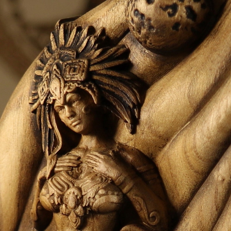 Op de afbeelding: Een houten sculptuur van een vrouw die een hoofdtooi draagt met ingewikkelde details. Het beeld is gesneden in een warme bruine kleur en heeft een getextureerd oppervlak.
