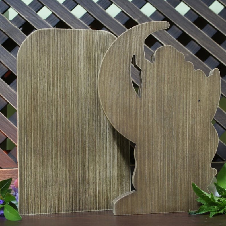 May include: Two wooden bookends, one shaped like a crescent moon and the other a rectangle. Both bookends have a rustic brown finish.