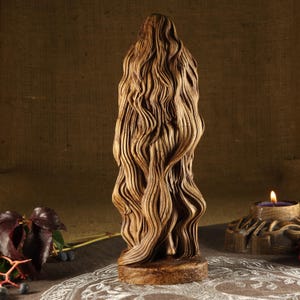 May include: A wooden sculpture of a woman with long, flowing hair. The sculpture is carved in a realistic style and has a natural wood finish.