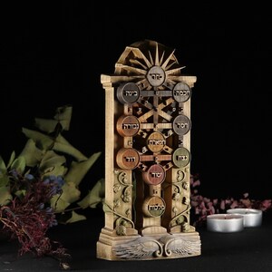 May include: A wooden sculpture of the Tree of Life, a Kabbalistic symbol. The tree is depicted with ten sefirot, or spheres, each containing a Hebrew letter and name. The sculpture is painted in shades of brown, green, and gold, and features intricate carvings of leaves and vines.