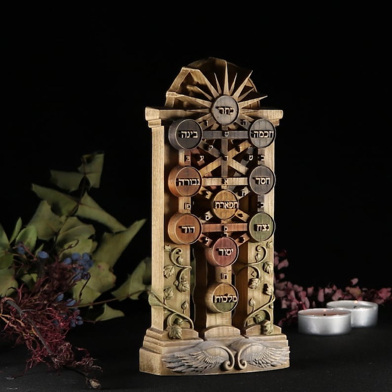 May include: A wooden sculpture of the Tree of Life, a Kabbalistic symbol. The tree is depicted with ten sefirot, or spheres, each containing a Hebrew letter and name. The sculpture is painted in shades of brown, green, and gold, and features intricate carvings of leaves and vines.