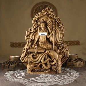 May include: A wooden sculpture of Amphitrite, the Greek goddess of the sea, sitting on a throne with a trident and an octopus. The sculpture is carved in a detailed style and has a warm brown colour.