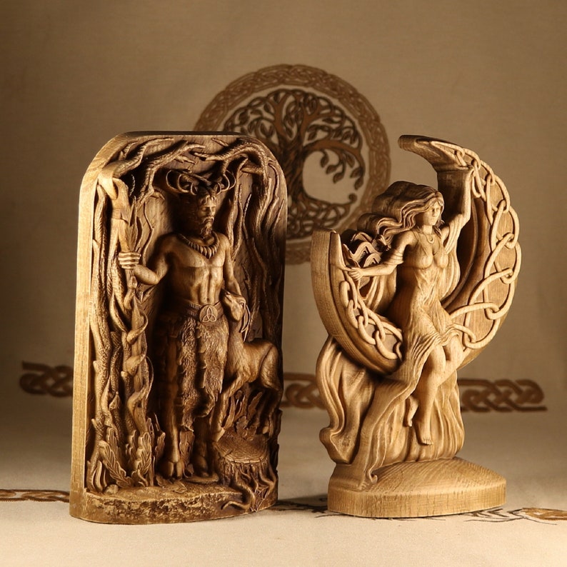 May include: Two wooden carvings depicting figures from Norse mythology. The first carving shows a horned god standing in a forest setting. The second carving shows a woman standing on a crescent moon.