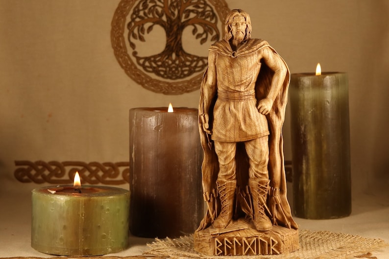 May include: A wooden statue of a Viking warrior with a beard and a cloak. The statue is standing on a wooden base with the word "BEORMOR" carved into it. The statue is surrounded by three candles.