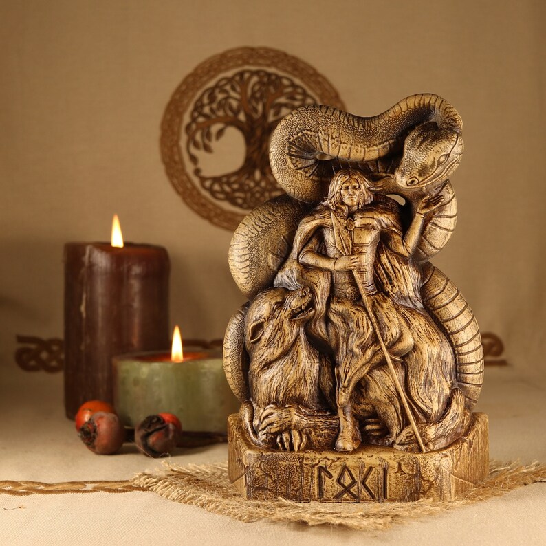 May include: A wooden statue of the Norse god Loki, depicted with a snake wrapped around him and two wolves at his feet. The statue is painted in shades of brown and gold and has a rune inscription on the base.