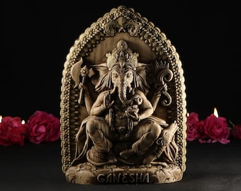 May include: A detailed, carved wooden sculpture of the Hindu deity Ganesha. The sculpture is painted in gold and brown tones and features intricate details. The sculpture is set against a black background with three lit candles and red roses in the foreground.