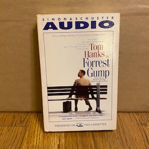 Peut inclure: Une cassette audio avec Tom Hanks dans le rôle de Forrest Gump du film Forrest Gump. Le boîtier est blanc avec des accents bleus et rouges. Le texte sur le boîtier indique "Tom Hanks est Forrest Gump" et "Maintenant un film majeur de Paramount".