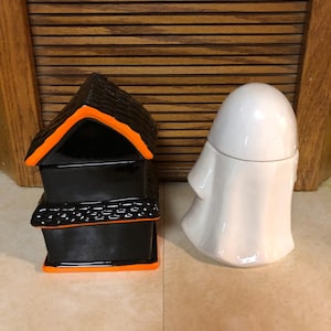 May include: Two Halloween themed ceramic containers. One is a black house with orange trim and the other is a white ghost.