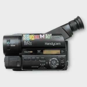 Könnte beinhalten: Schwarze Sony Handycam mit "SPIDER-MAN" und "160x DIGITAL ZOOM" Text. Verfügt über einen Sucher, Bedienelemente und ein digitales Display mit der Anzeige "0:00:00". Die Kamera hat ein "Video 8 XR" Label.