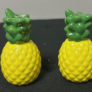 Può includere: Un paio di saliere e pepiere in ceramica a forma di ananas. Le saliere e le pepiere hanno un corpo giallo brillante con una superficie strutturata e una parte superiore verde. Un'aggiunta divertente a qualsiasi cucina.