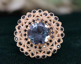 May include: A gold ring with a large blue gemstone surrounded by a halo of smaller black gemstones. The ring has a delicate, intricate design.