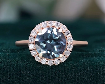 May include: A rose gold engagement ring with a large blue topaz center stone surrounded by a halo of smaller diamonds.