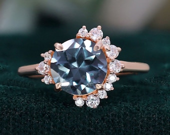 May include: A rose gold engagement ring with a large, round, blue gemstone surrounded by a halo of smaller, round, white gemstones.