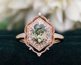 May include: A rose gold ring with a hexagonal setting featuring a green moss agate gemstone surrounded by a halo of smaller diamonds.