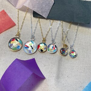 May include: Six necklaces with different colored resin pendants. The pendants are round and filled with colorful confetti-like pieces. The necklaces are on a white background.