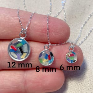May include: Three silver necklaces with different sized pendants. The pendants are clear glass spheres filled with colorful confetti. The necklaces are 12 mm, 8 mm, and 6 mm in diameter.