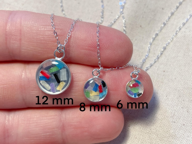 May include: Three silver necklaces with different sized pendants. The pendants are clear glass spheres filled with colorful confetti. The necklaces are 12 mm, 8 mm, and 6 mm in diameter.