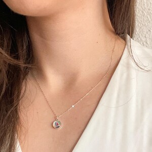 May include: A silver chain necklace with a round pendant featuring a colorful geometric design.
