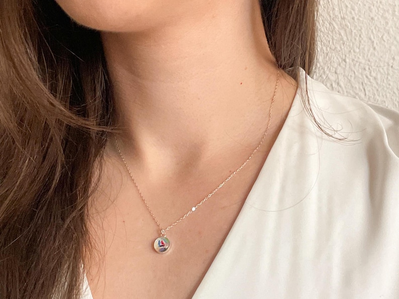May include: A silver chain necklace with a round pendant featuring a colorful geometric design.