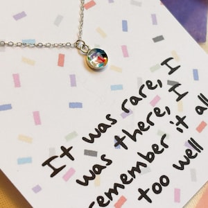 May include: A silver necklace with a small round pendant featuring a colorful confetti design. The necklace comes with a card that reads "It was rare, I was there, I remember it all too well."